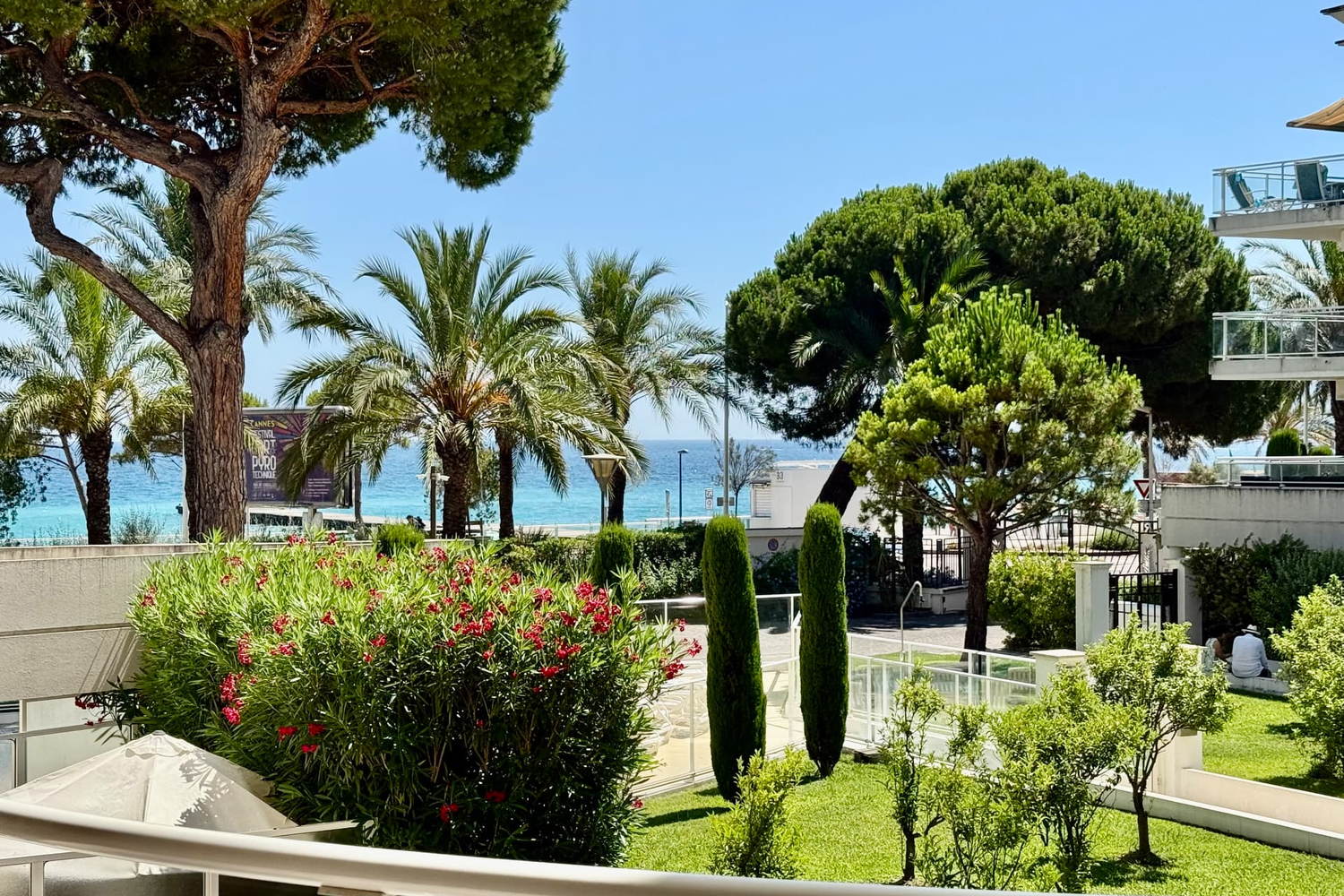 Jardins et piscine de la Résidence Royal Palm à Cannes-la-Bocca, avec la mer en arrière-plan